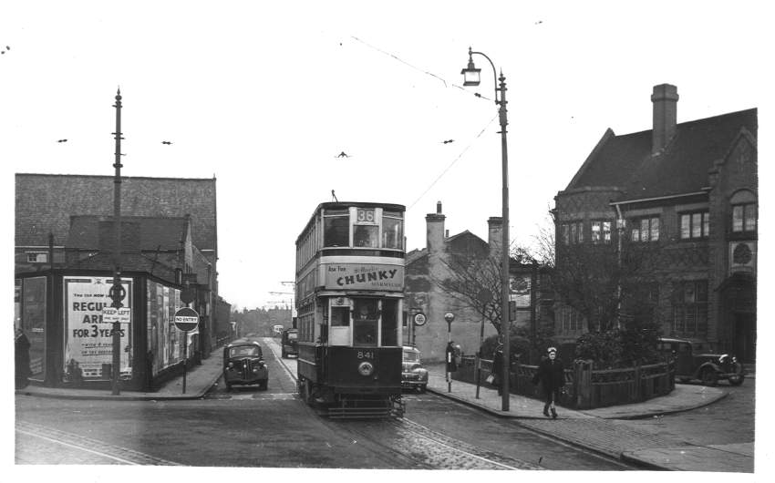 a black and white image of a double decker tram pasing a pub on the Pershore Road in Birmingham